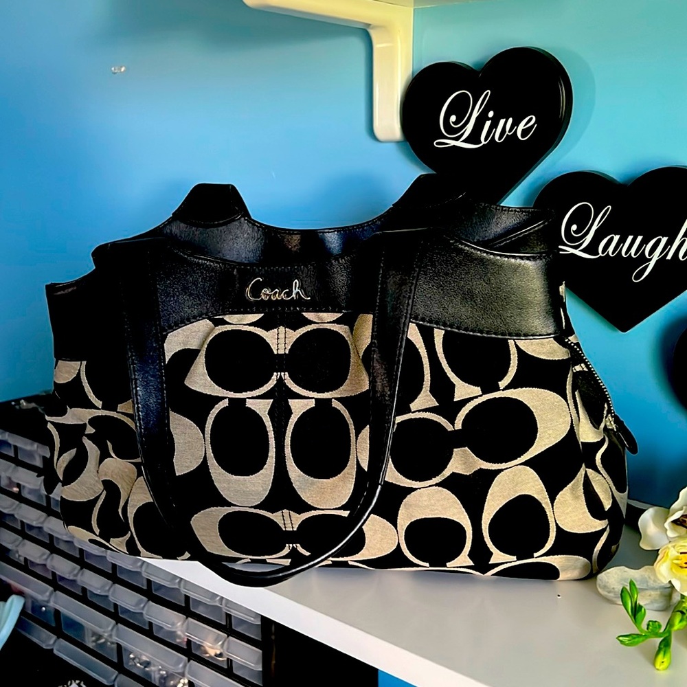 This is a coach shoulder bag that is black and taupe.
